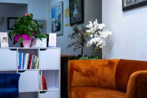 Gemütlicher Raum mit orangefarbenem Sofa, Bücherregal und weißen Orchideen